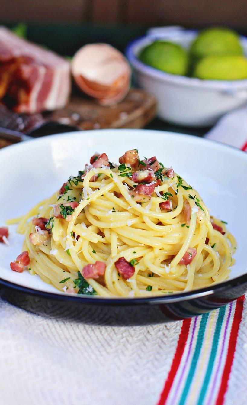 Spaghetti mit Limetten-Carbonara mit Pancetta angerichtet auf einem tiefen Teller