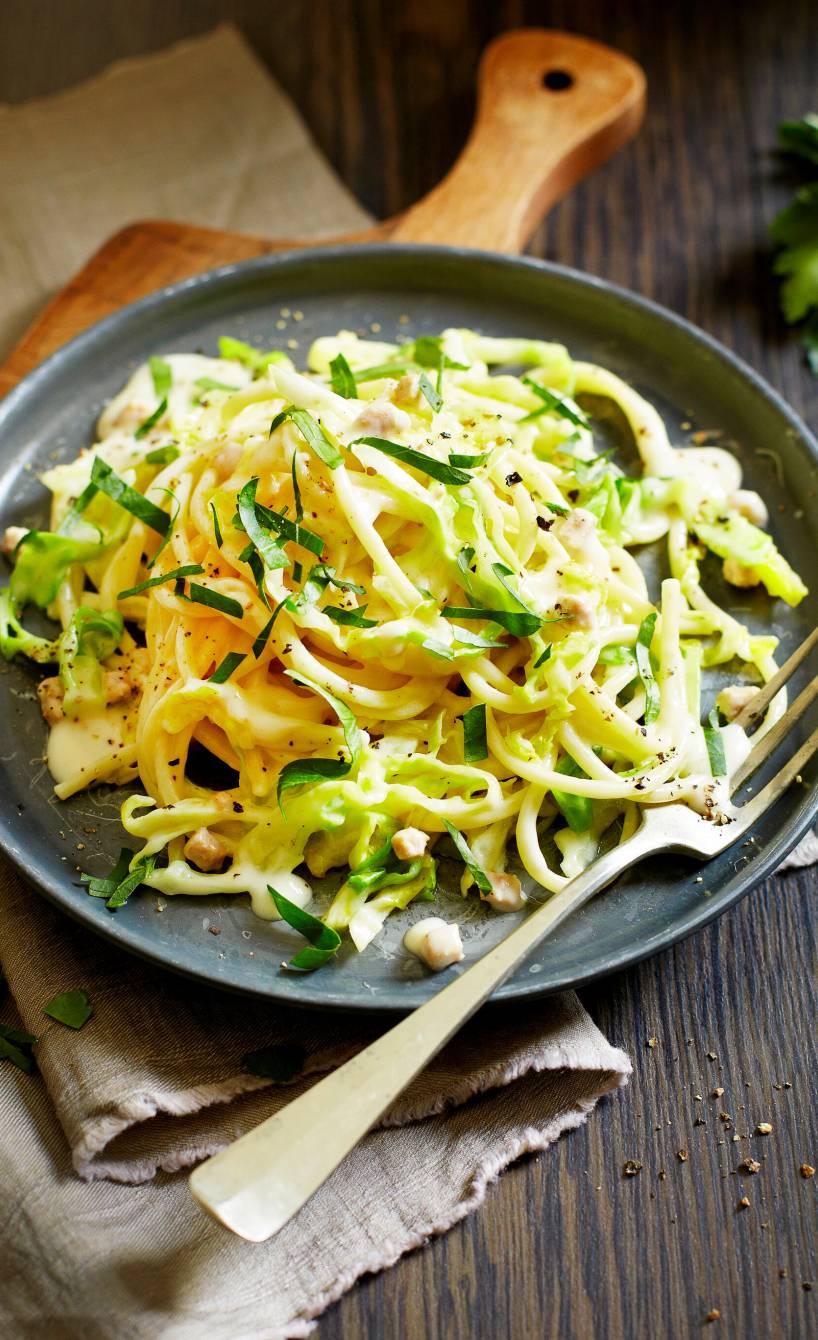 Spaghetti mit Spitzkohl, Speck und Sahnesoße angerichtet auf einem Teller