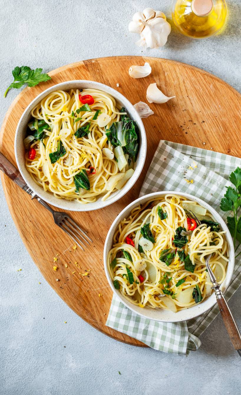 Zwei Portionen Spaghettini aglio e olio mit Mangold von oben auf einem Holzbrett