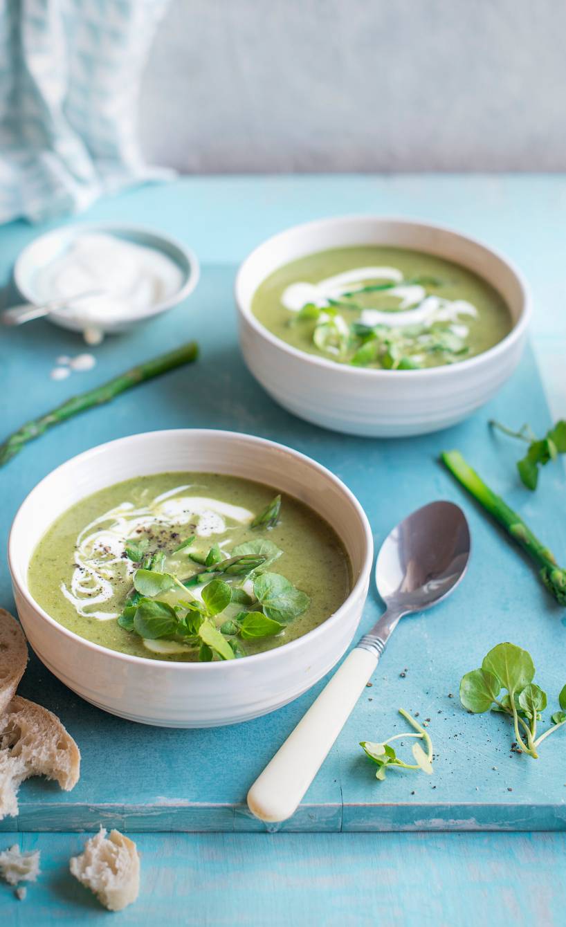 Selbstgekochte italienische Spargelcremesuppe mit Mascarpone in zwei Suppenschalen auf einem Tisch, daneben Ciabattascheiben