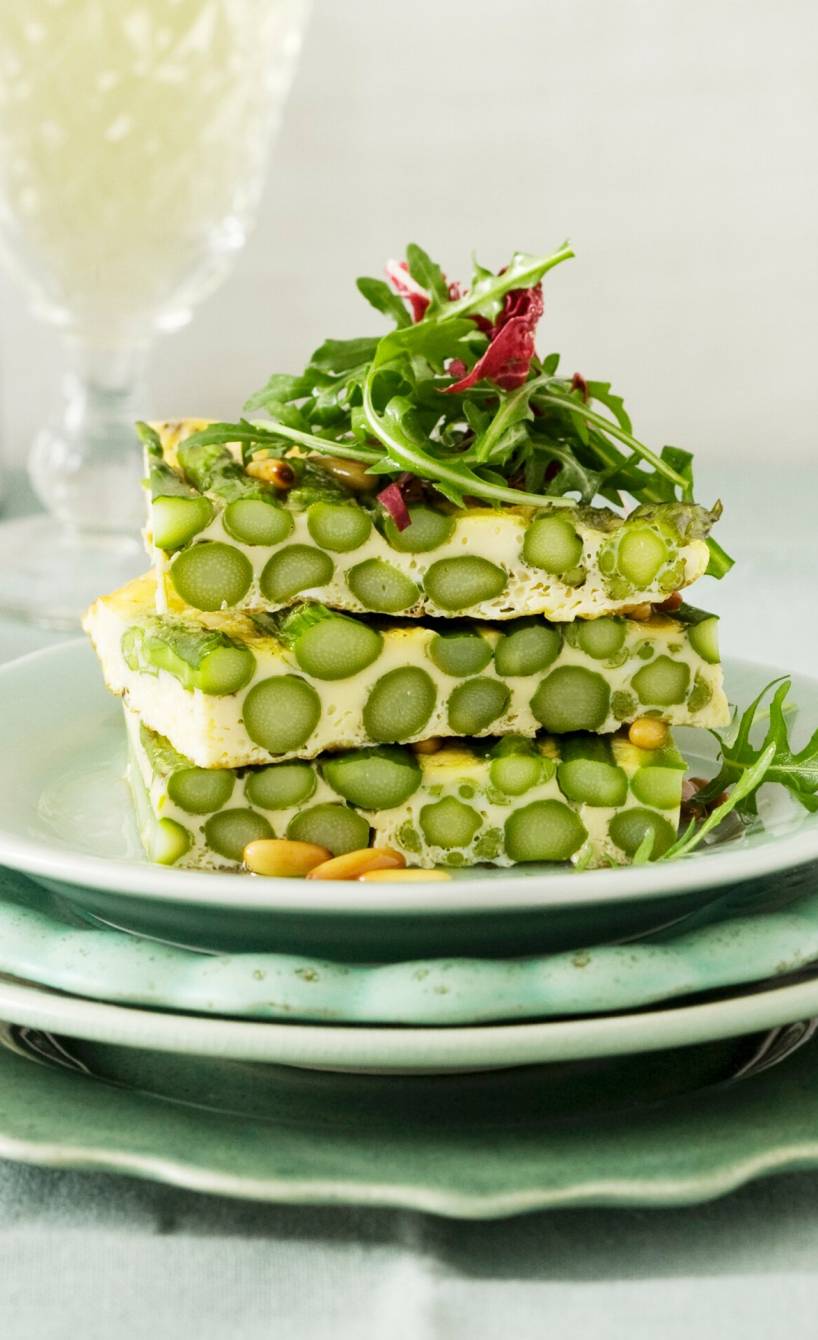 Spargelfrittata mit grünem Spargel in Stücke geschnitten gestapelt auf einem Teller