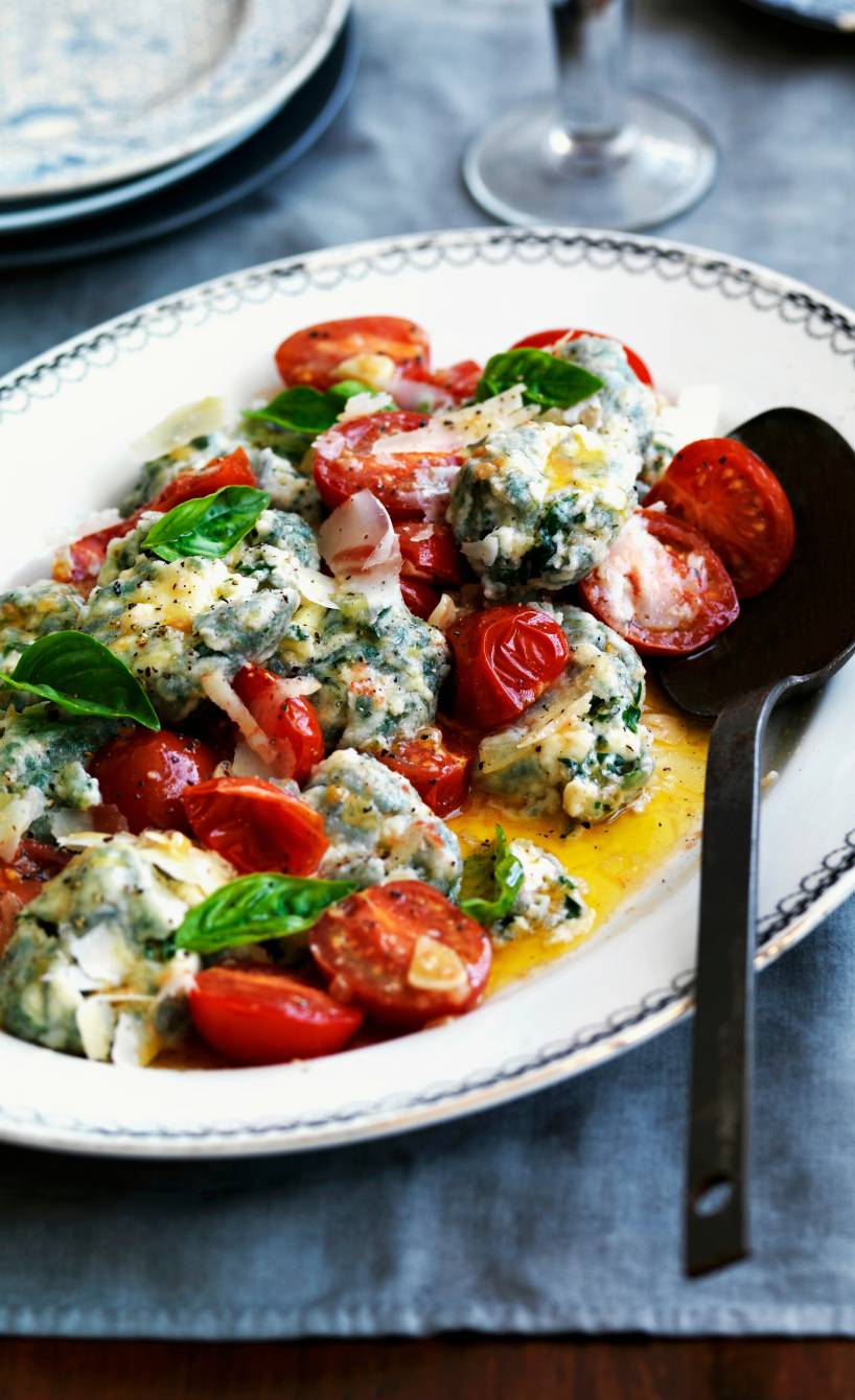 Überbackene Spinat-Ricotta-Nocken mit Tomaten und Käsekruste angerichtet auf einem Teller