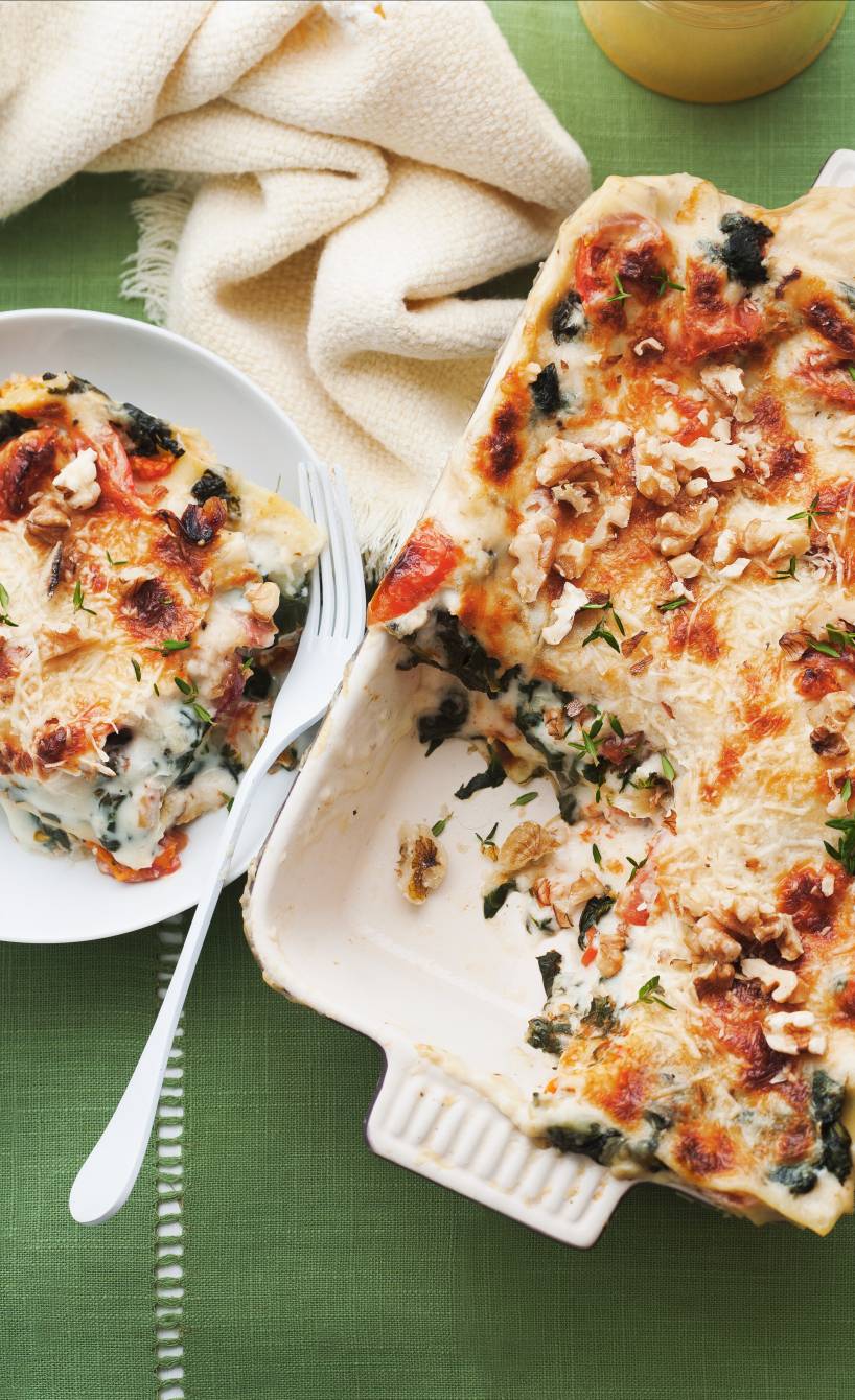 Angeschnittene Spinatlasagne mit Ziegenkäse, Feigen und Walnüssen in einer Auflaufform