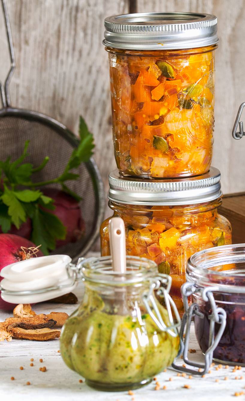 Pilzpesto und verschiedene andere eingemachte Pestos und Chutneys auf einem Tisch mit Zutaten