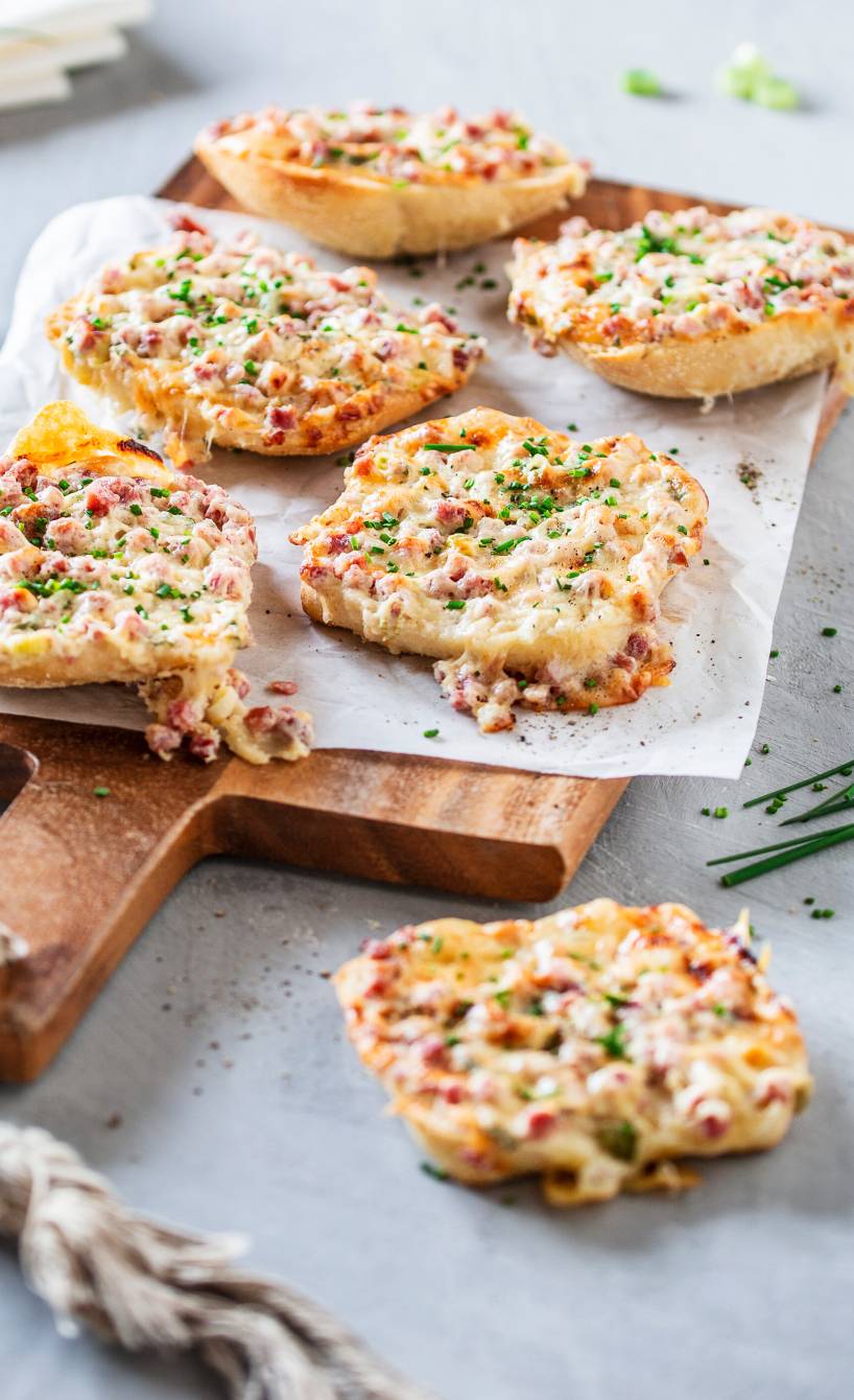 Halbe Flammkuchenbrötchen auf einem Holzbrett