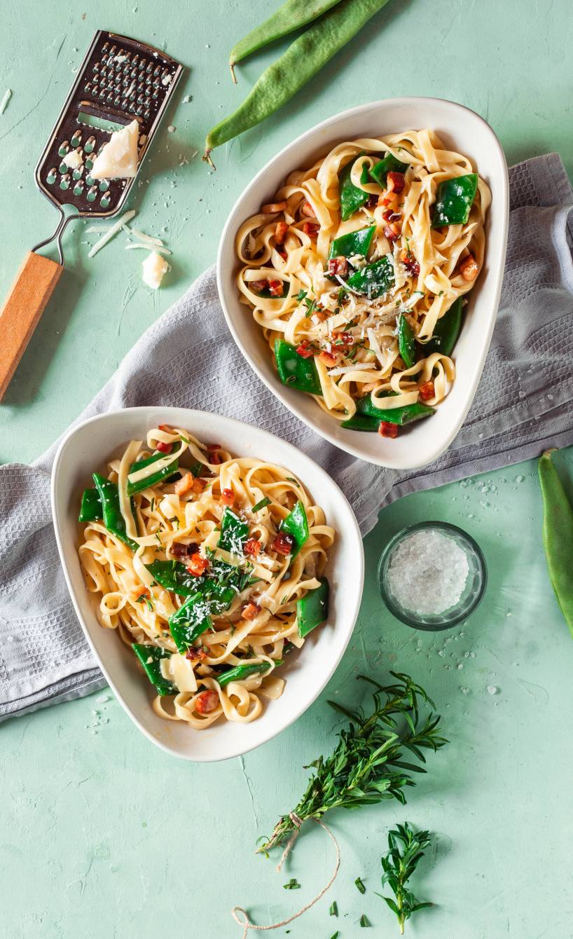 Tagliatelle mit Carbonara mit grünen Bohnen angerichtet auf zwei Pastatellern