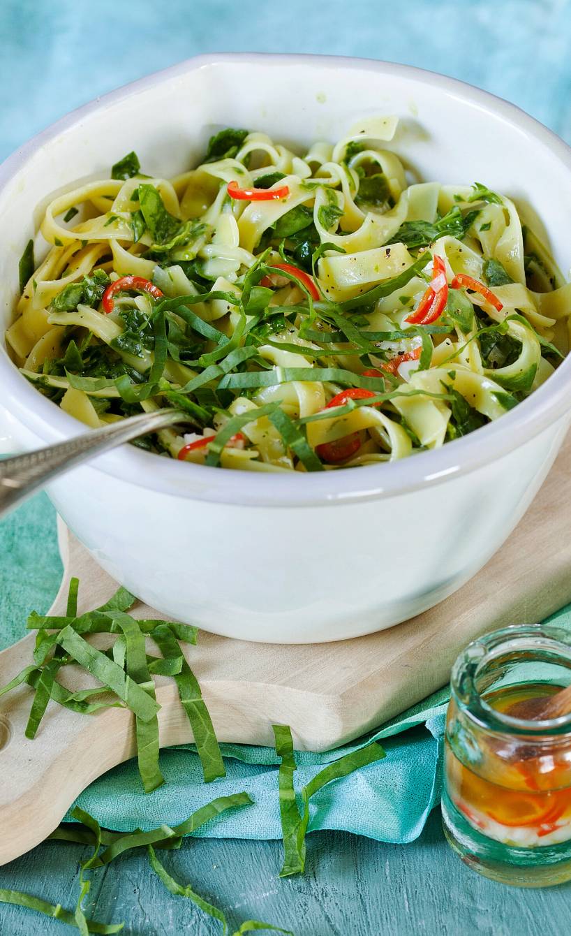 Bärlauchnudeln in einem Topf getoppt mit frischem Bärlauch, Peperoncino-Streifen und Parmesan