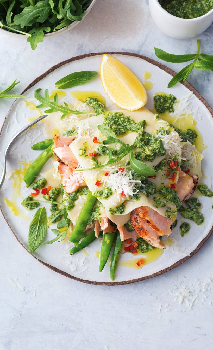 Teller-Lasagne mit Lachs und Pesto auf einem Tisch, daneben ein Schälchen Rucola