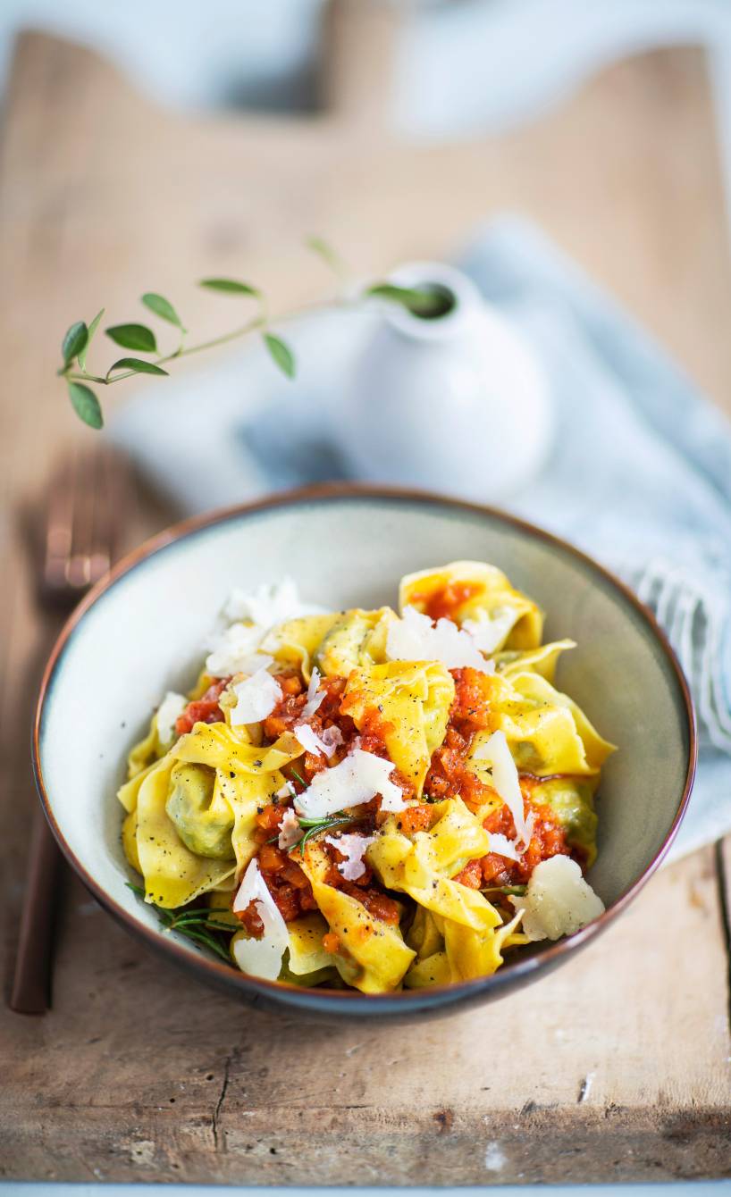 Tortelloni in einem tiefen Teller mit Tomatensauce und Parmesan getoppt