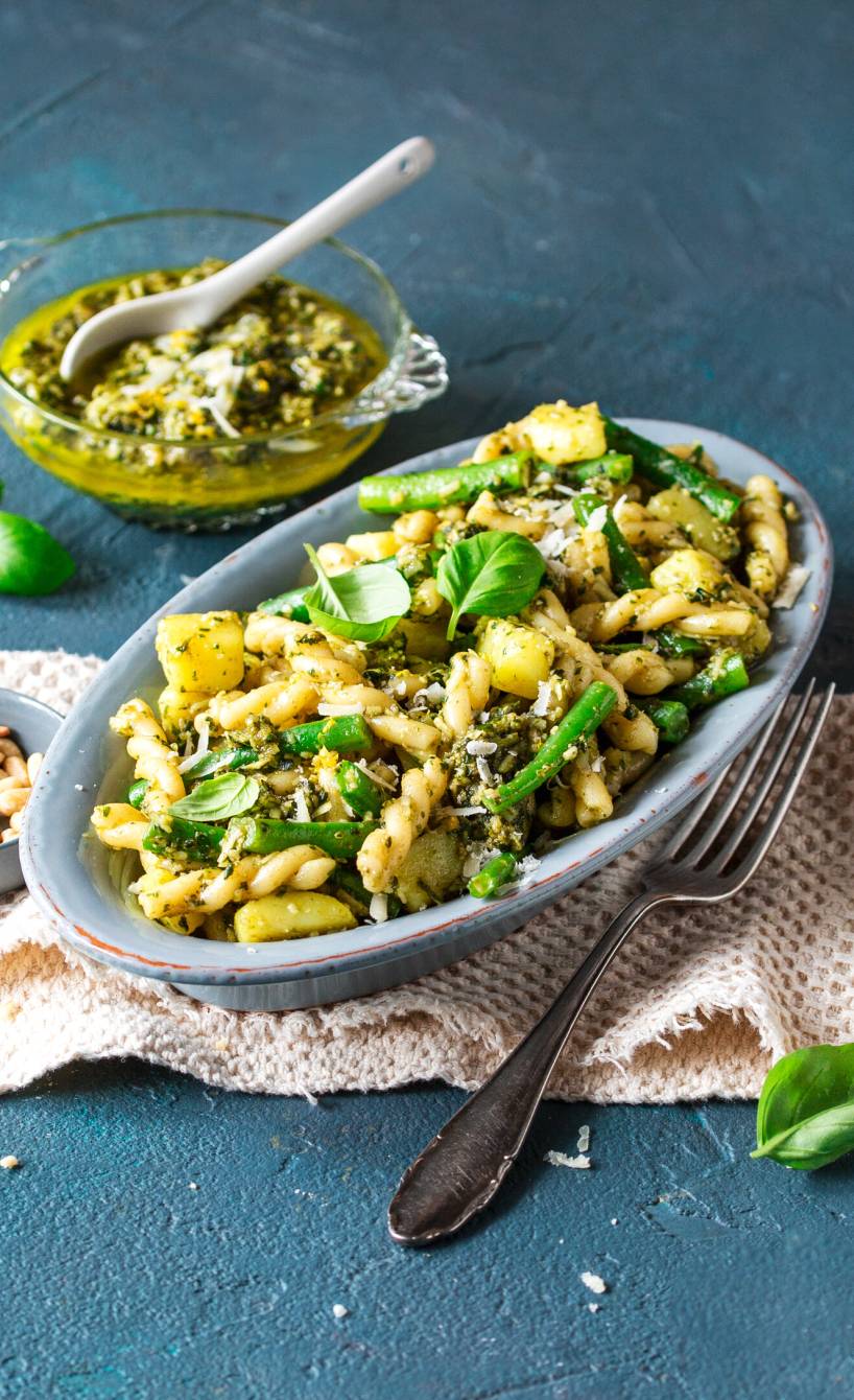 Pasta alla Genovese auf einem ovalen Teller, daneben Pesto in einem Glas