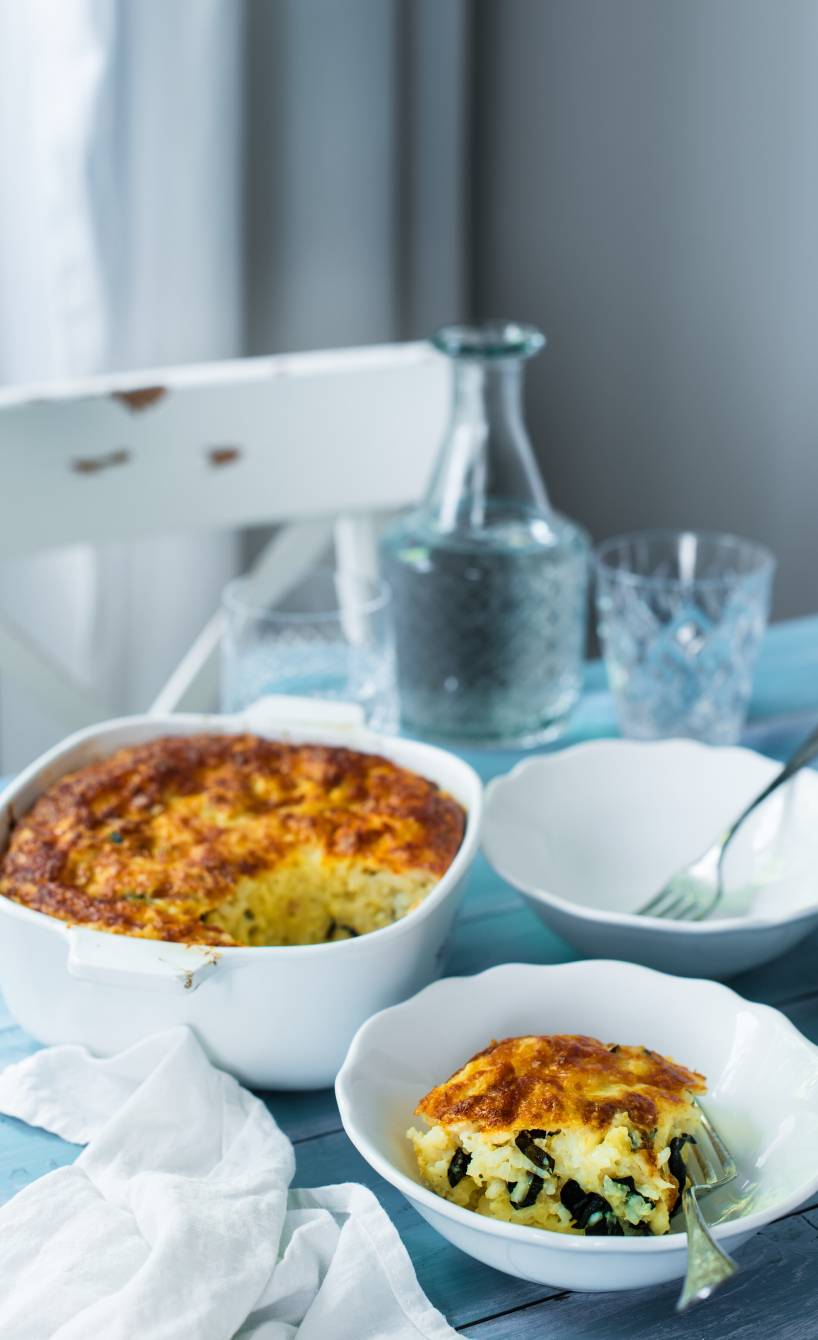3-Käse-Risotto mit Mangold in einer Auflaufform, ein Stück davor auf einem Teller