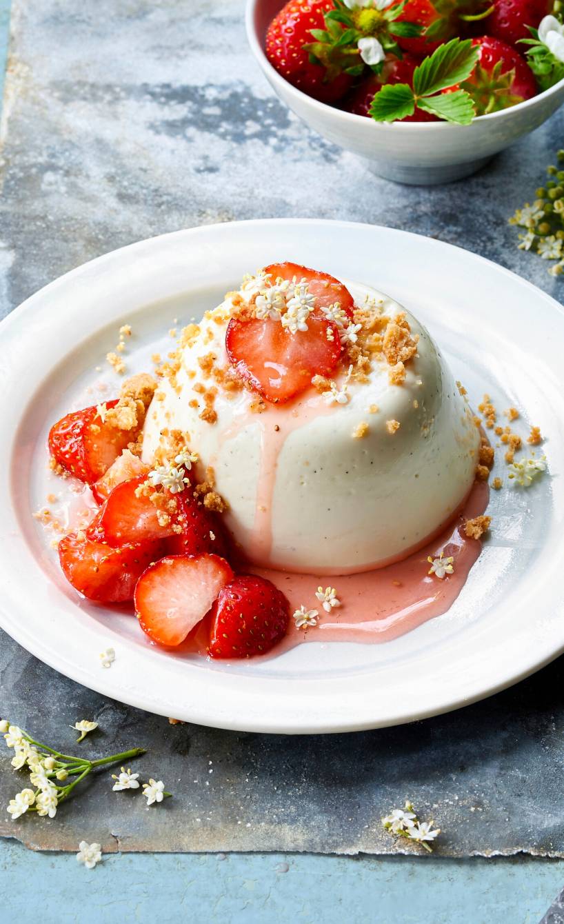 Holunderblüten-Pannacotta garniert mit Erdbeeren und Sauce auf einem Teller
