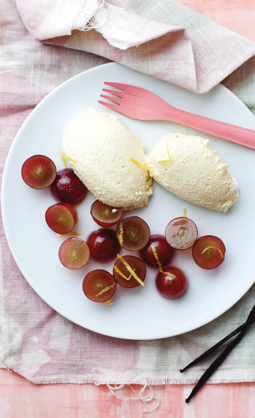 Zwei Nocken Vanillemousse angerichtet mit Traubensalat auf einem Dessertteller