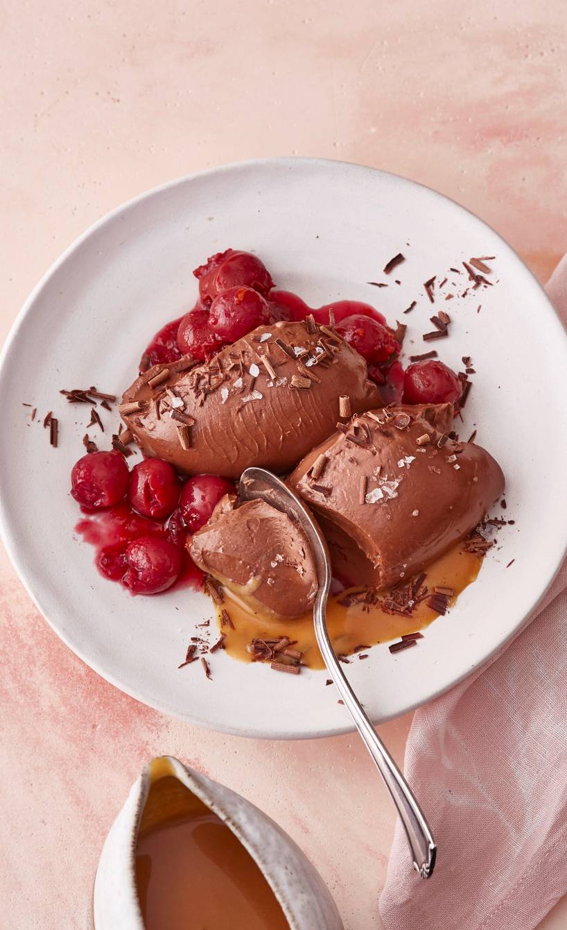 Vegane Schokomousse-Nocken angerichtet auf einem Dessertteller mit Kirschkompott und Karamellsoße