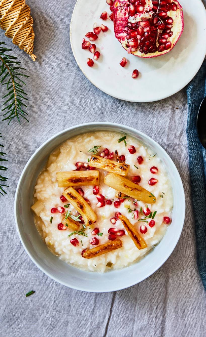 Veganes Schwarzwurzelrisotto getoppt mit Granatapfelkernen in einer Schale auf einem weihnachtlich dekorierten Tisch