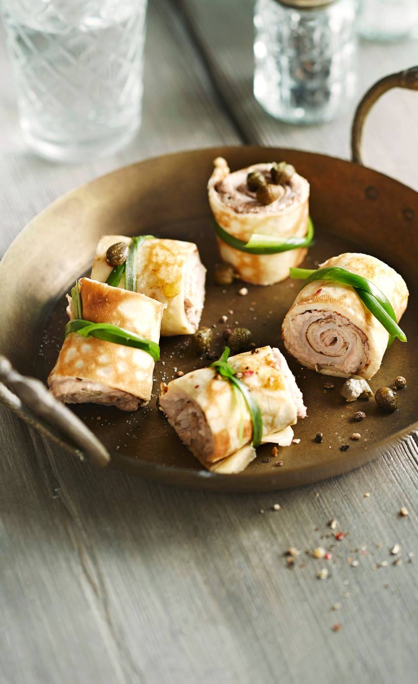Crêpe-Röllchen mit Vitello-Tonnato-Füllung und Schnittlauch-Schnur angerichtet in einer kupfernen Pfanne