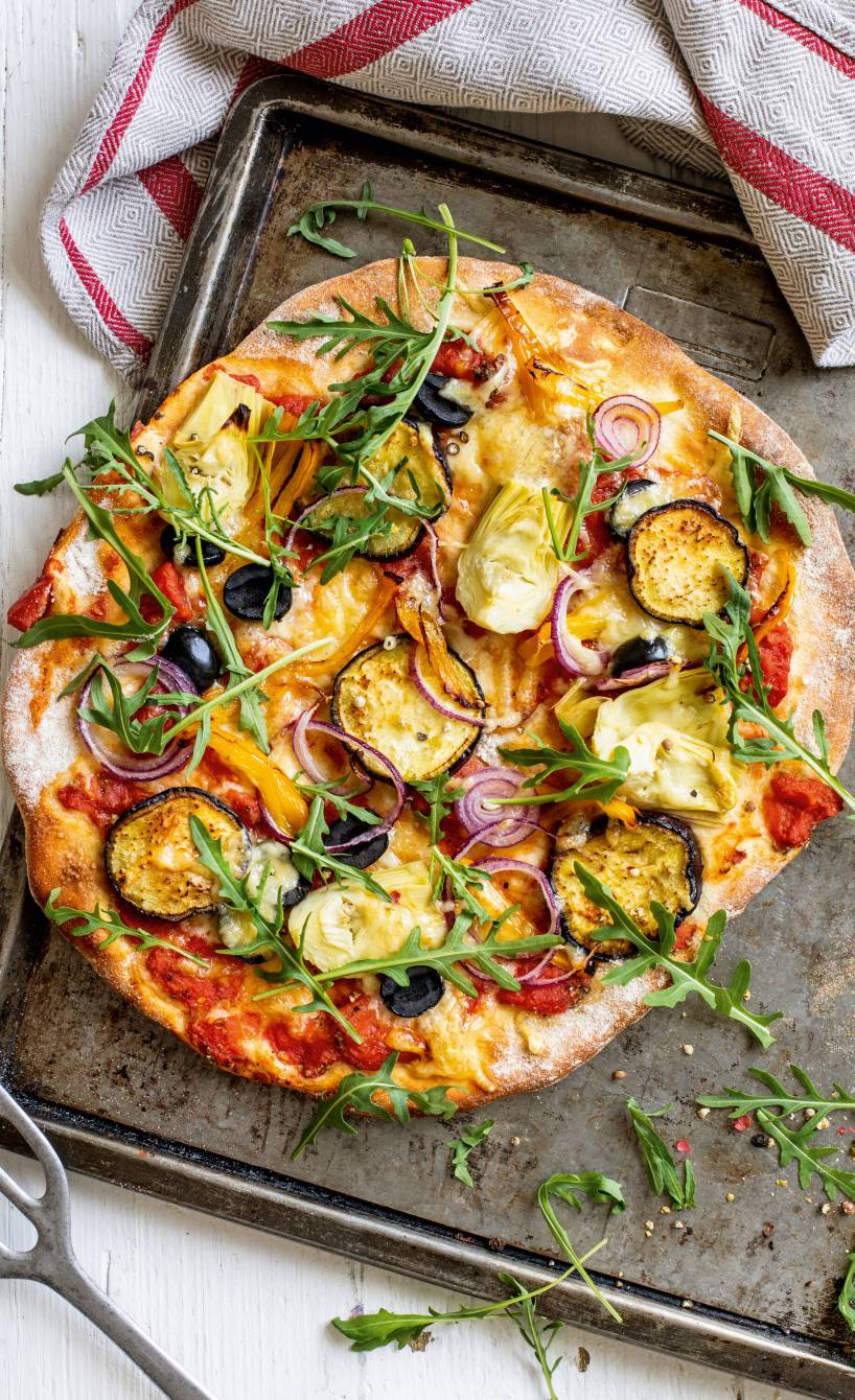 Runde Vollkorn-Pizza belegt mit Gemüse und Mozzarella auf einem Backblech