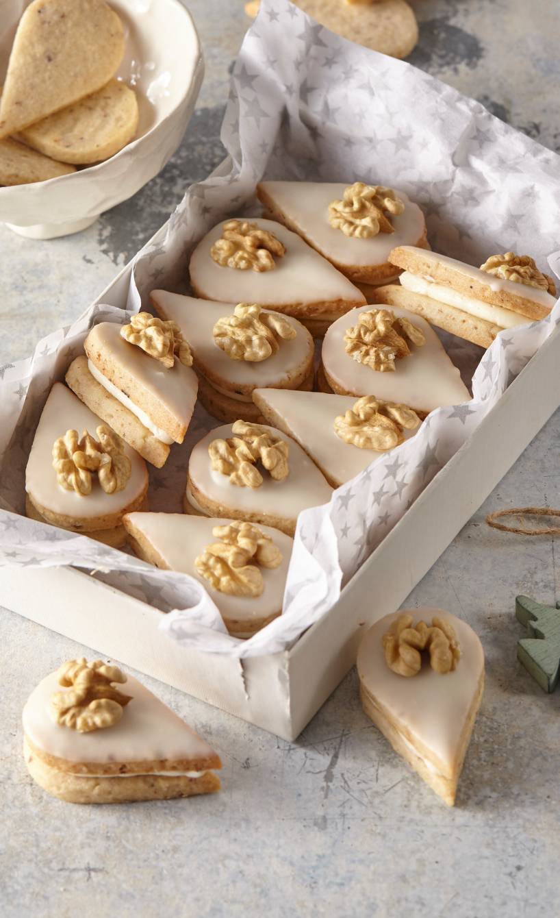 Walnussplätzchen in Tropfenform in einer Schachtel, daneben Weihnachtsdekoration