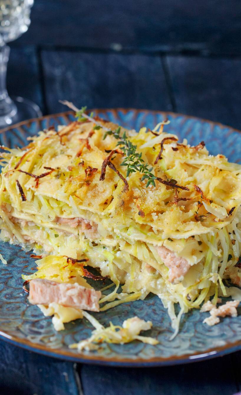 Stück weißer Lasagne auf einem blauen Teller, Lachsüllung erkennbar