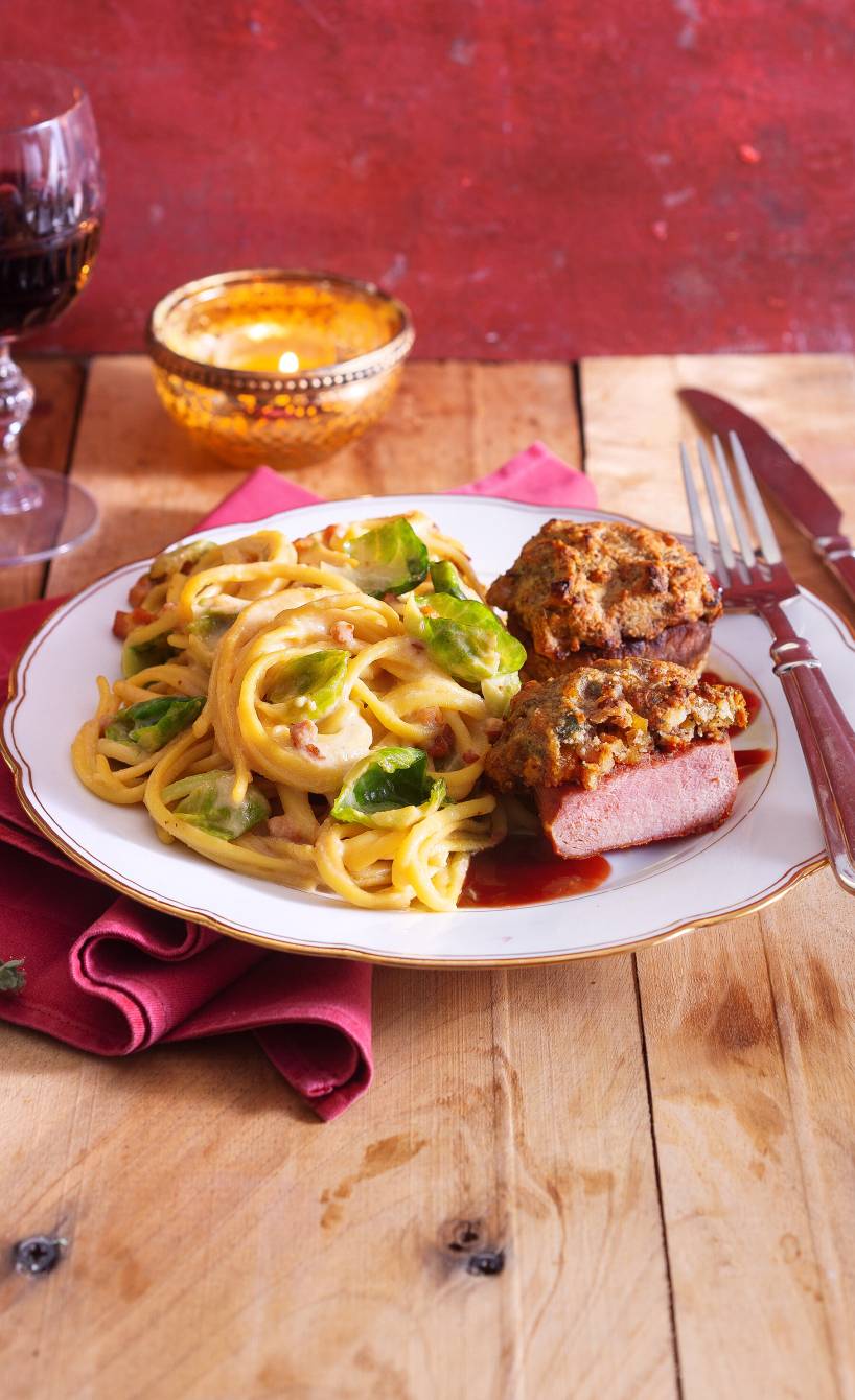 Zwei gratinierte Wildschweinmedaillons angerichtet mit Rosenkohl-Carbonara auf einem Teller