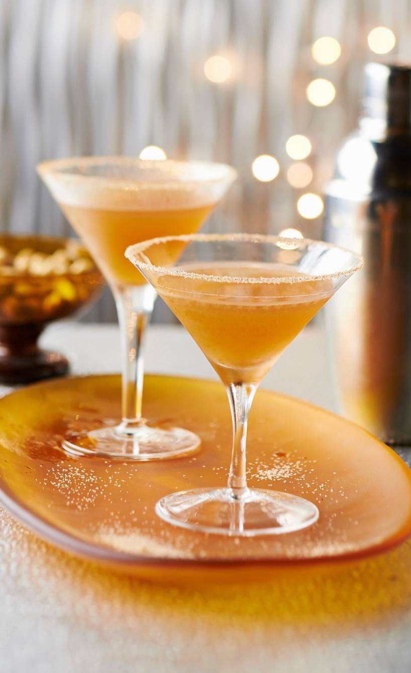 Zwei Martinis auf einem festlich dekorierten Tisch neben einem Cocktailshaker