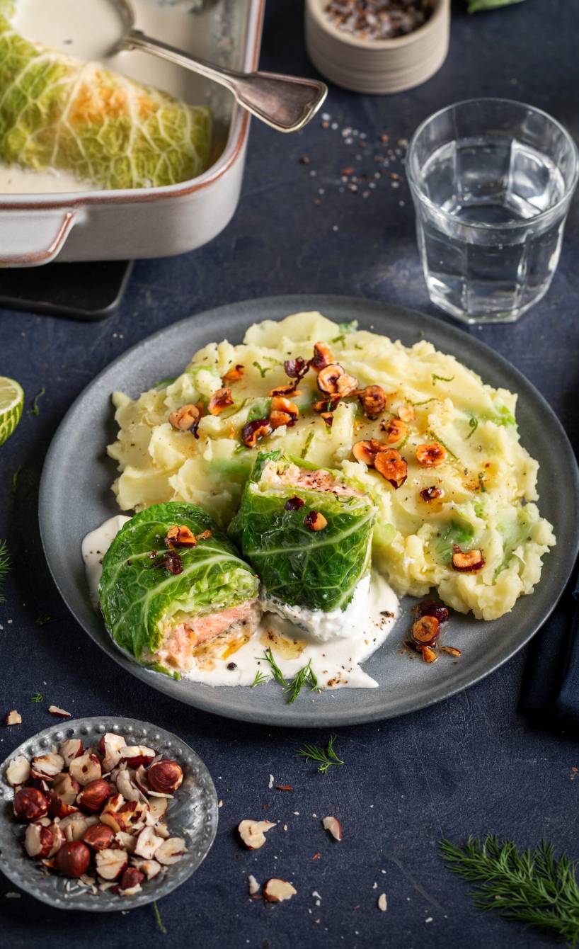 Wirsing-Lachs-Involtini mit Kartoffelstampf und Haselnussbutter angerichtet auf einem Teller