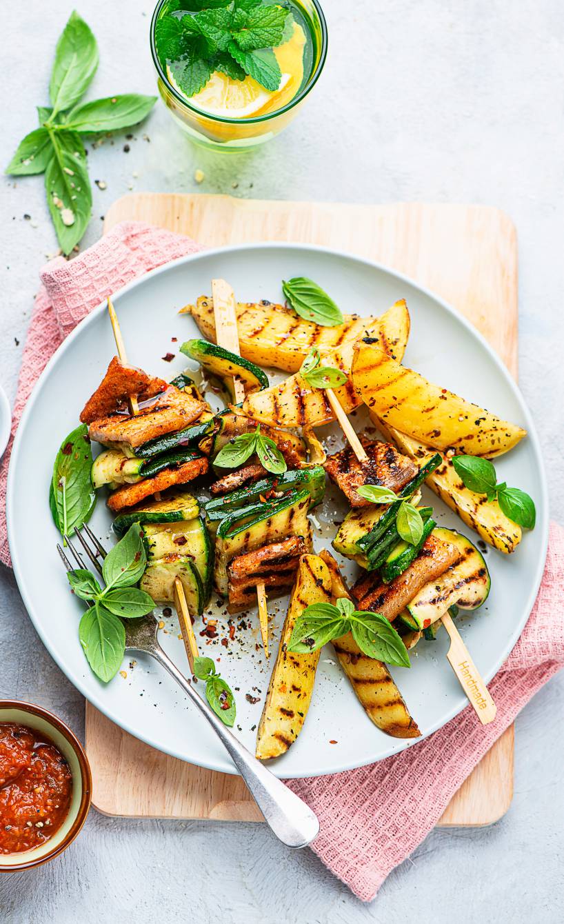 Gegrillte Zucchini-Bauchfleisch-Grillspieße angerichtet auf einem Teller mit Kartoffelspalten