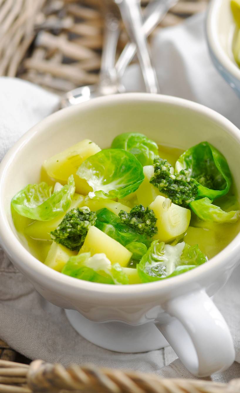 Italienischer Rosenkohleintopf in zwei Suppenschalen mit Kartoffeln, darauf und daneben grünes Pesto