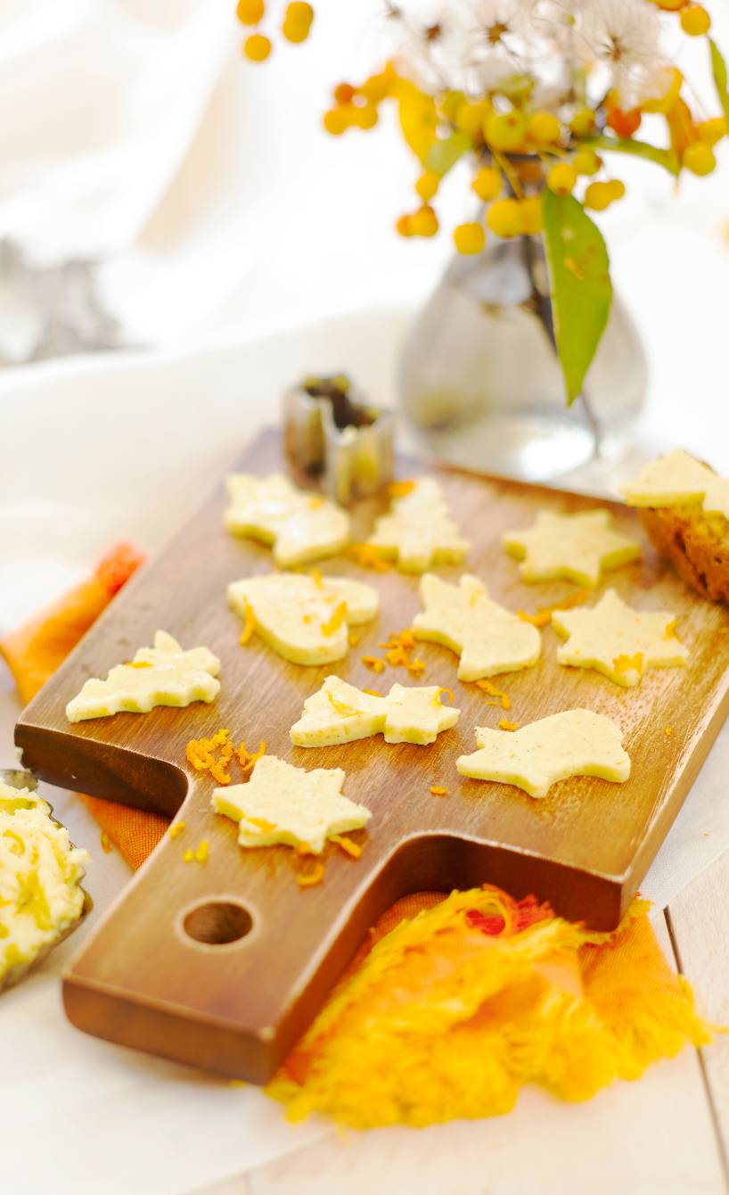 Weihnachtsbutter mit Orangen-Vanille-Aroma ausgestochen zu Weihnachtsbäumen, herzen und Sternen auf einem Holzbrett