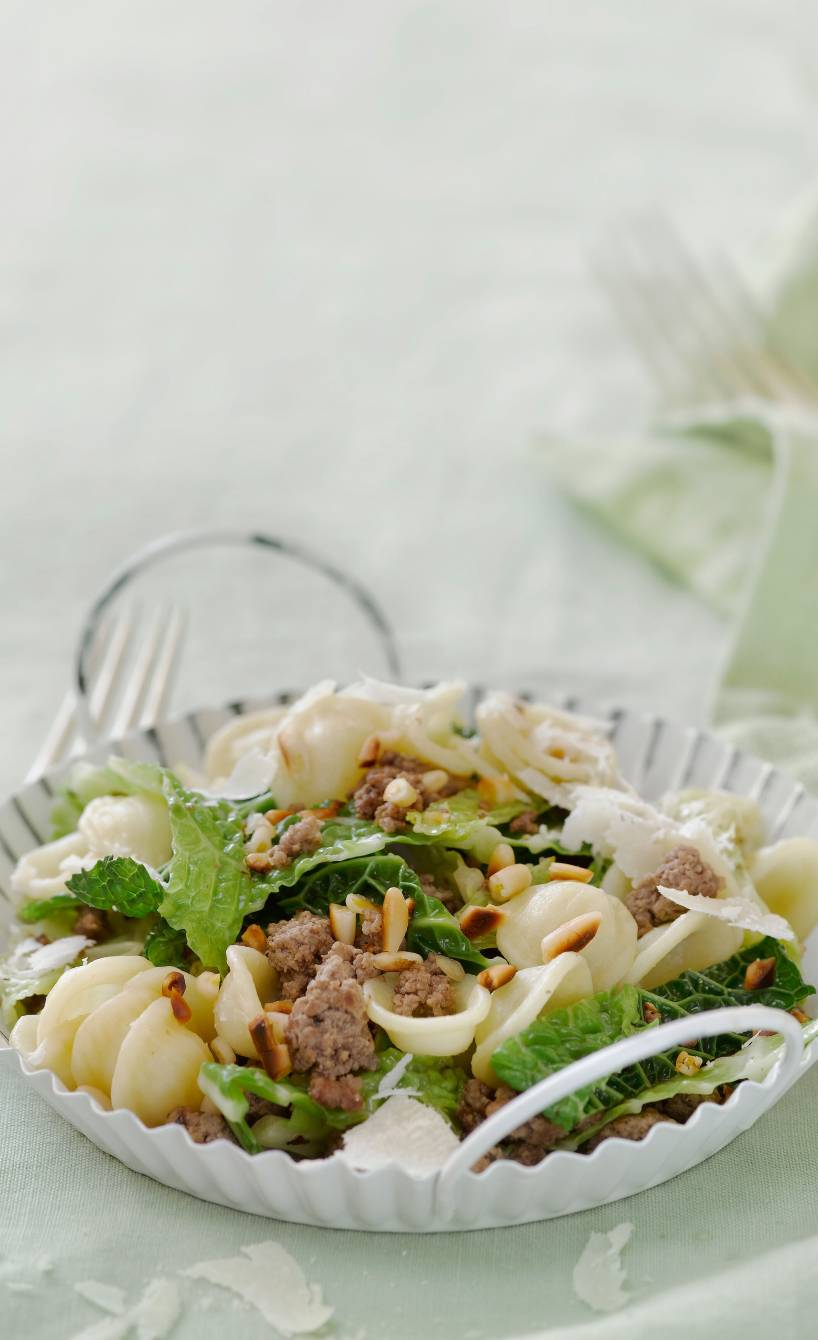 Pfanne mit Wirsing, Hackfleisch und Orechiette getoppt von Parmesan und Pinienkernen auf einem Tisch