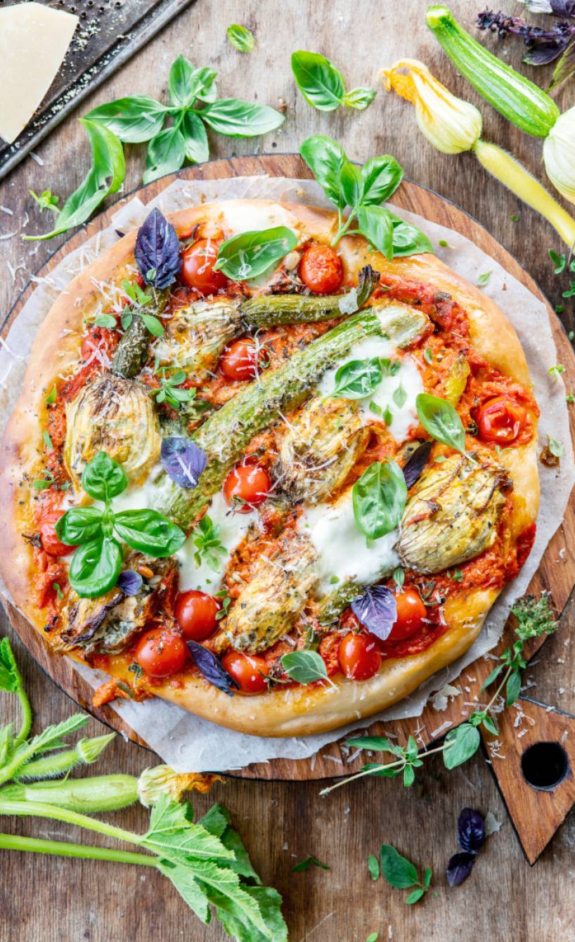 Pizza mit Tomaten und gefüllten Zucchiniblüten