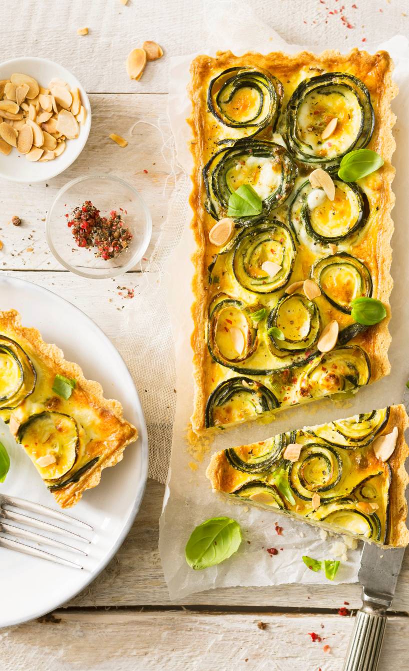 Zucchini-Quiche angeschnitten auf einem Holzbrett