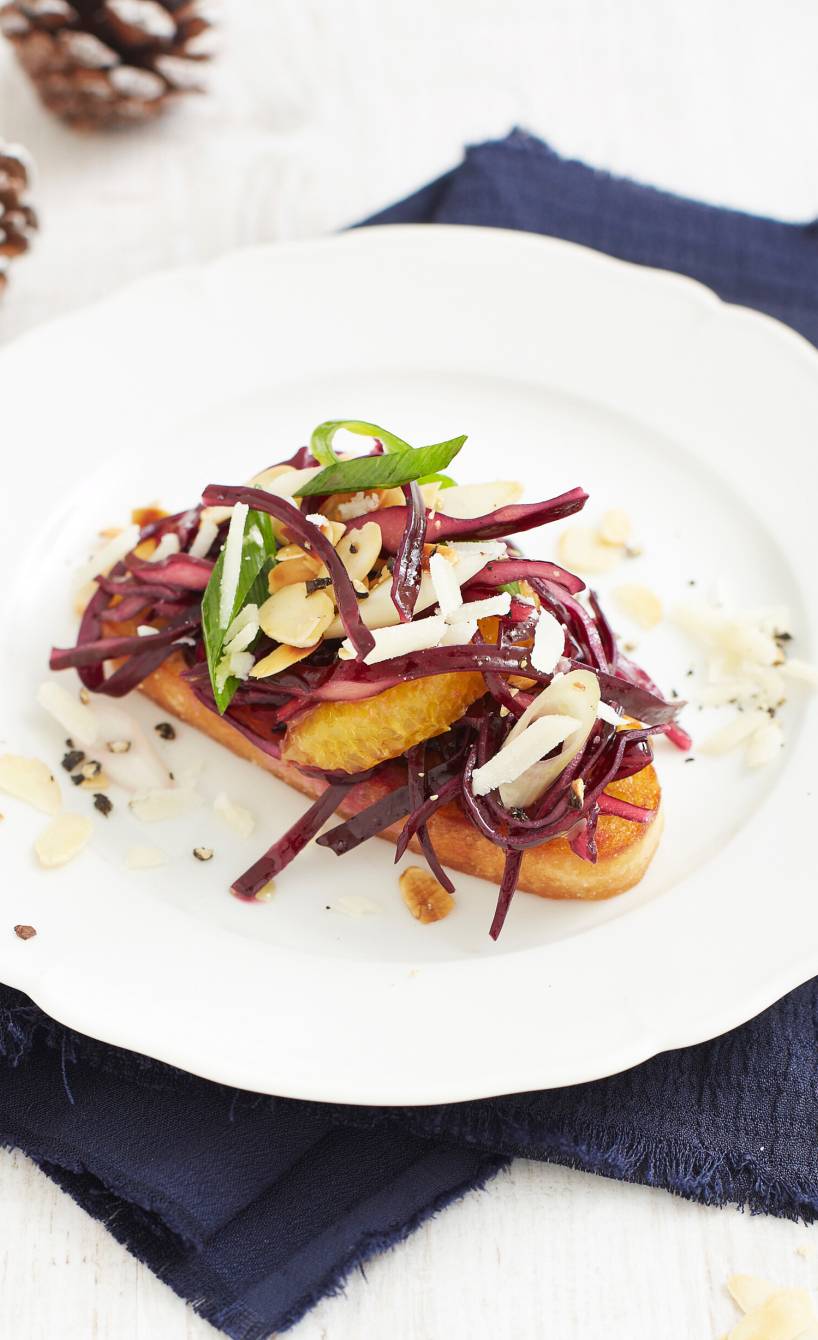 Ein Rotkohl-Crostini auf einem Teller getoppt mit Orange, Mandeln und Parmesan