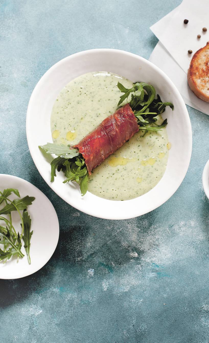  Rucola-Kartoffelcremesuppe in einem Suppenteller mit Einlage aus Rucola-Parmaschinken-Röllchen