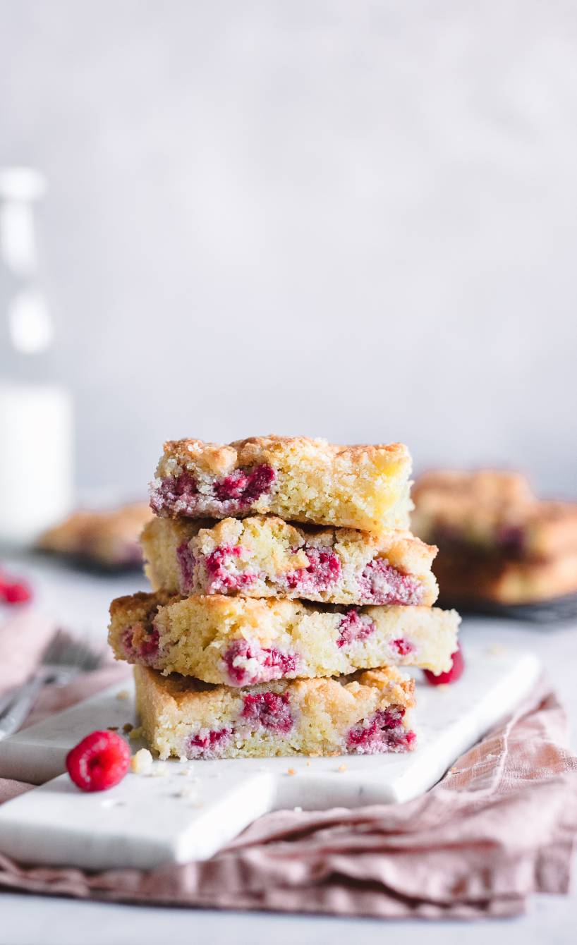 Vier Stücke Streuselkuchen mit Himbeeren vom Blech gestapelt auf einem Kuchenteller