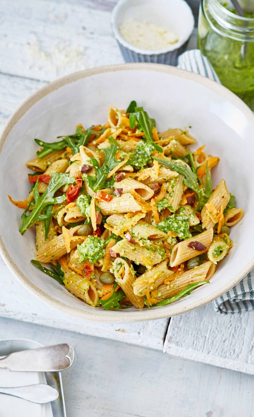 Vollkorn-Nudel-Salat mit Rucola, getrockneten Tomaten und grünem Pesto angerichtet auf einem tiefen Teller