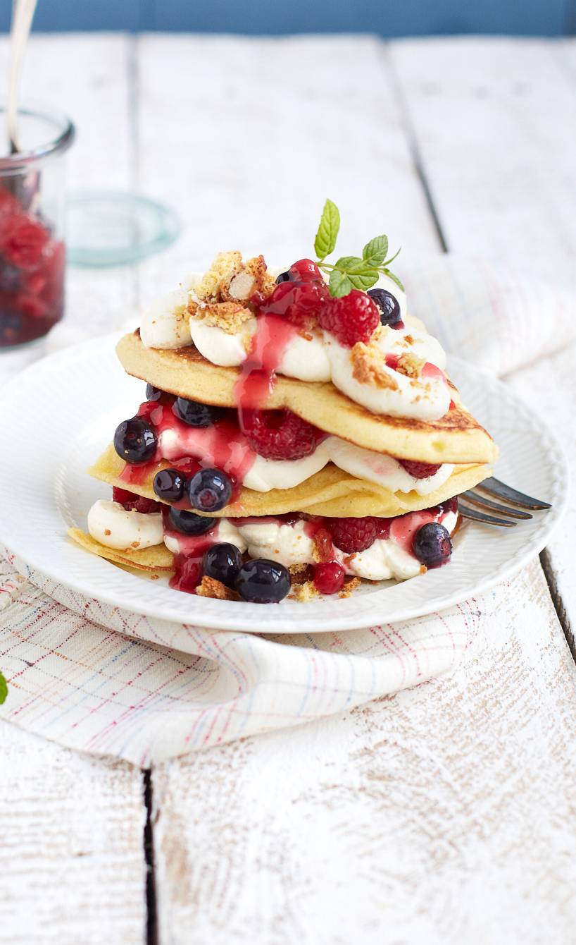 Lasagne geschichtet aus Pfannkuchen, Beeren und Frischkäsecreme getoppt mit Minze auf einem Teller