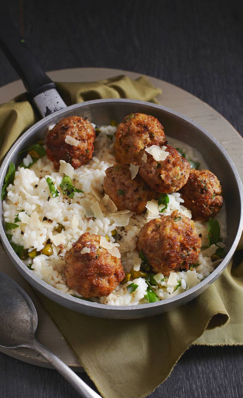 Weißweinrisotto in einer Pfanne getoppt von Wildschweinhackbällchen und Parmesanspänen