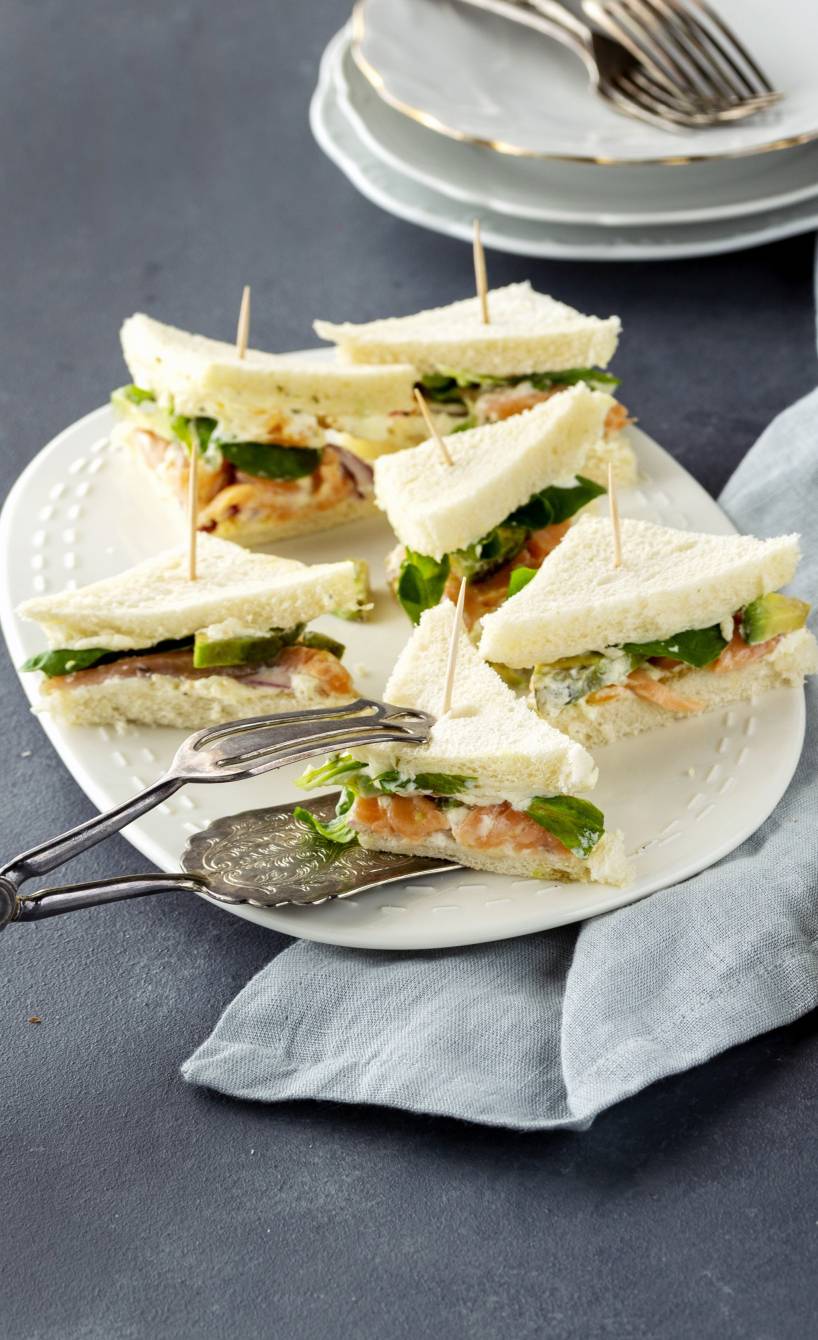 Eine Platte mit Tramezzini mit Lachs, Avocado und Kapern