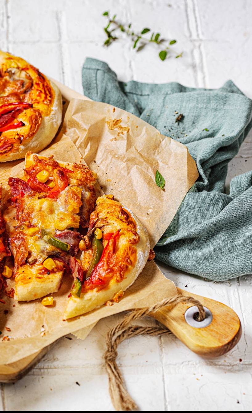 Zwei ovale Pizzen angeschnitten auf einem Holzbrett