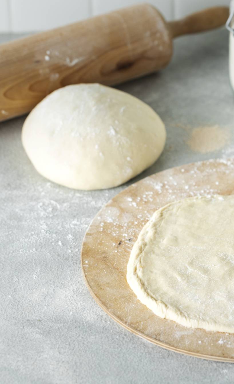 Pizzateig aus Semola ausgerollt auf einem Holzbrett