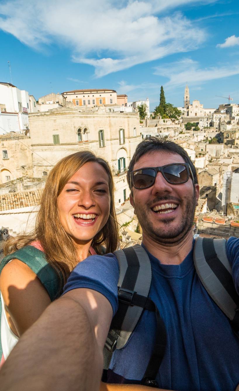 Pärchen macht ein Selfie während einer Rundreise durch Süditalien, im Hintergrund Matera