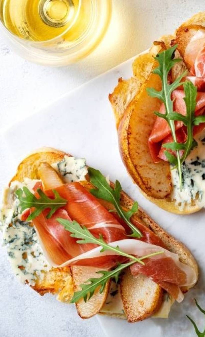 Crostini mit Birne, Gorgonzola und Parmaschinken auf einem Tisch