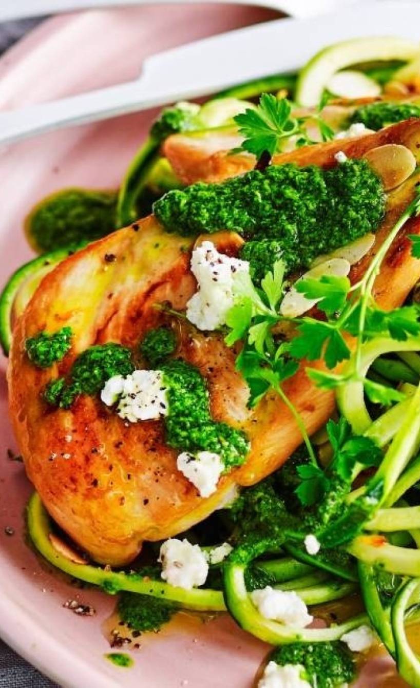 Zucchininudeln und Hähnchen auf einem rosa Teller