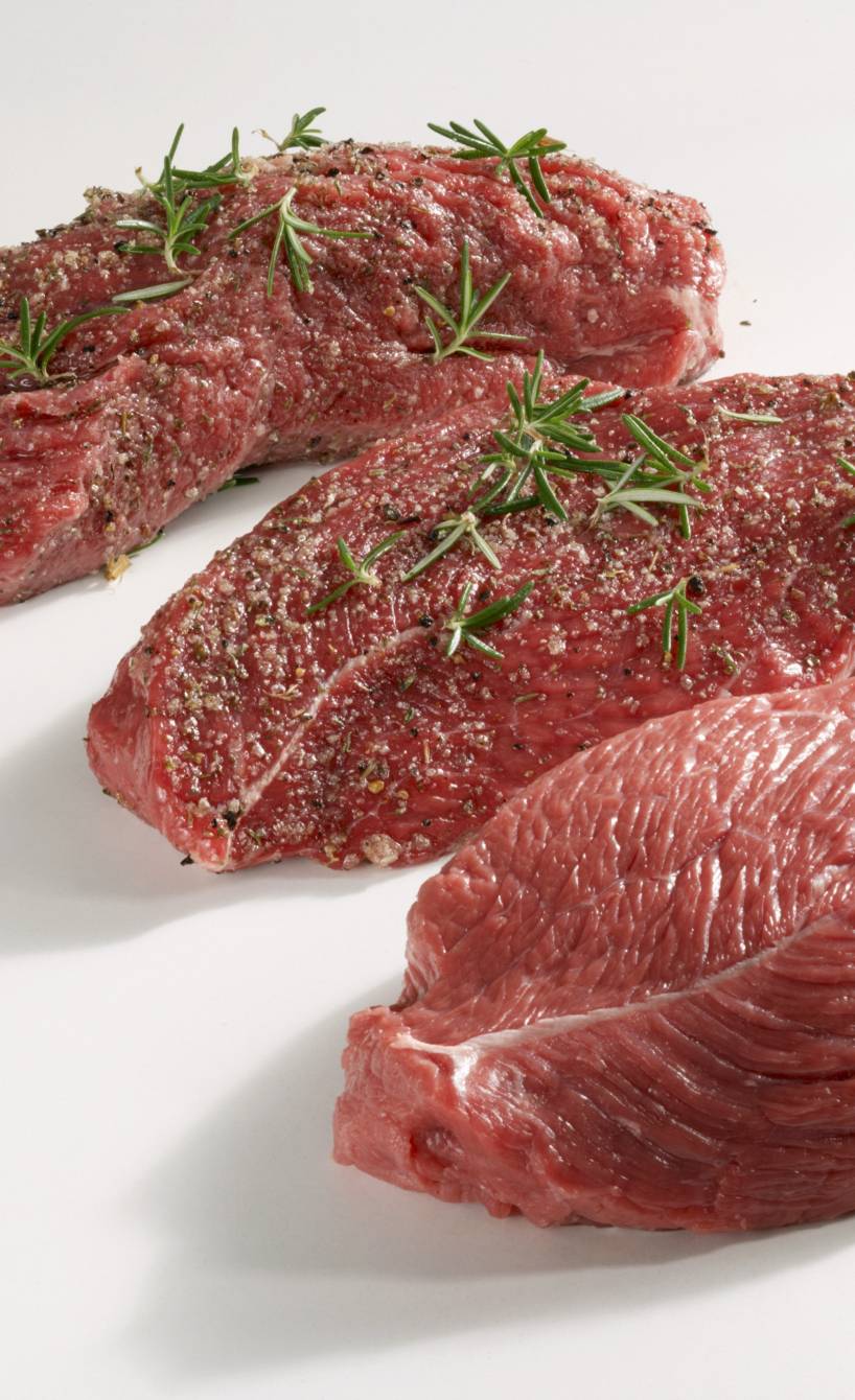 Drei rohe Stücke Tagliata vom Rind auf einem Tisch