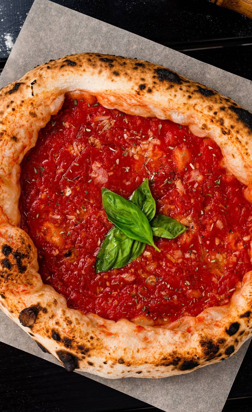 Runde Pizza Marinara im Ganzen auf einem Holzbrett garniert mit Basilikum
