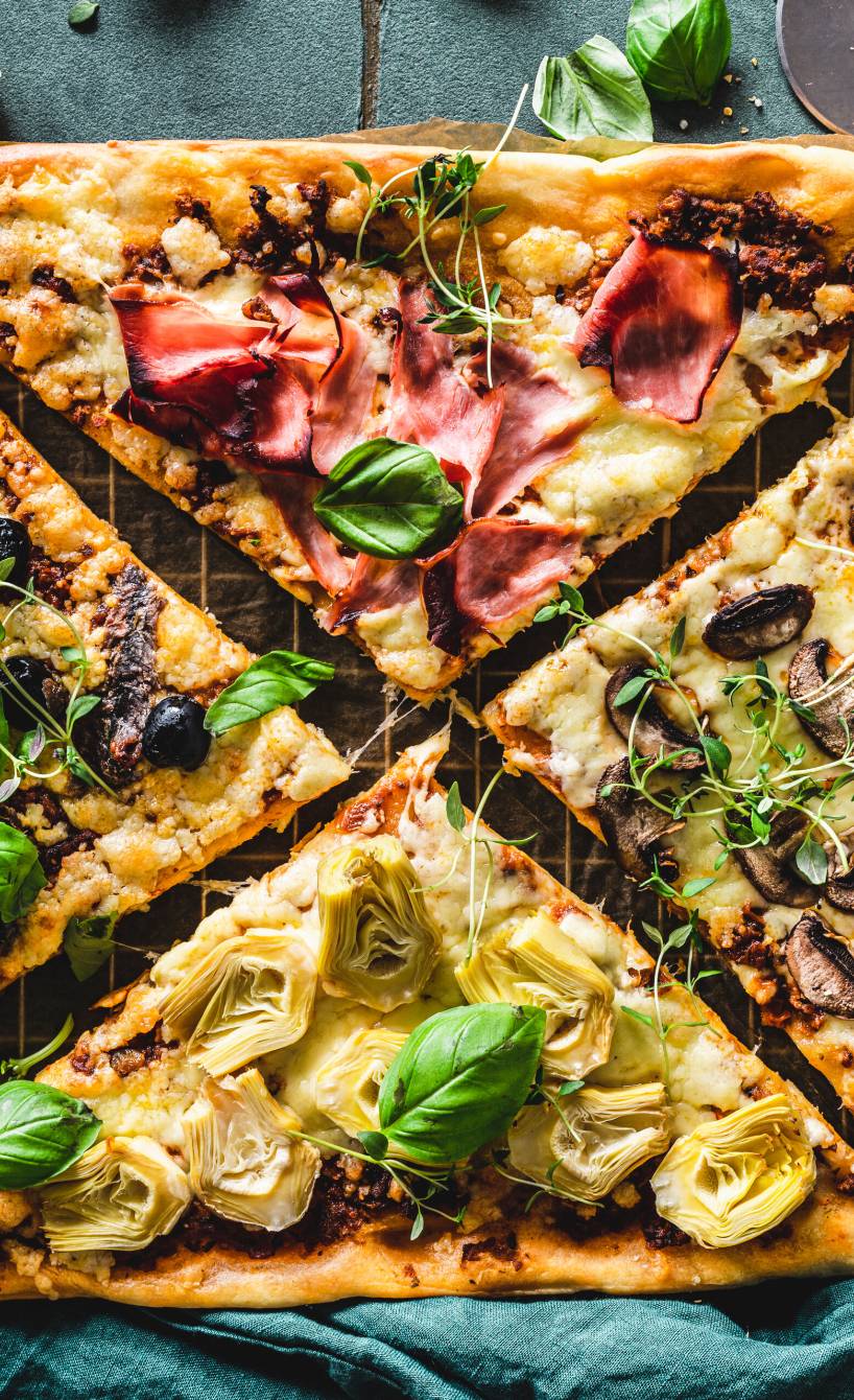 Pizza Quattro Stagioni auf einem Backblech in vier Teile geschnitten