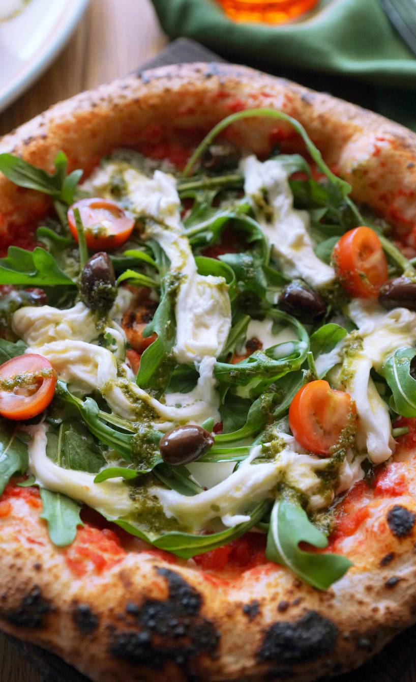 Runde Stracciatella Pizza im Ganzen auf einem teller getoppt mit Rucola
