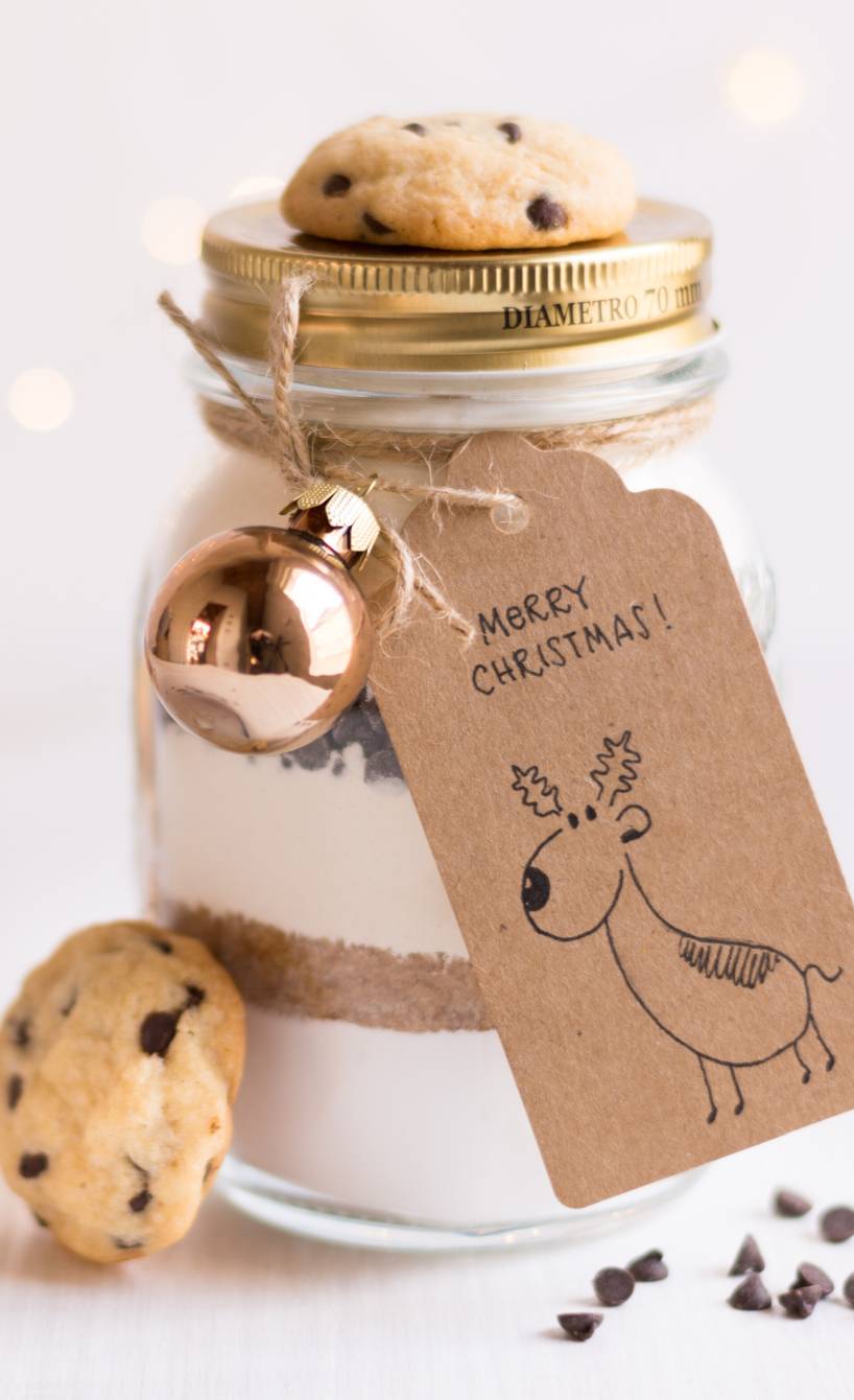 Backmischung im Glas für Schoko-Nuss-Kekse dekoriert mit fertigen Keksen und einem Geschenkanhänger