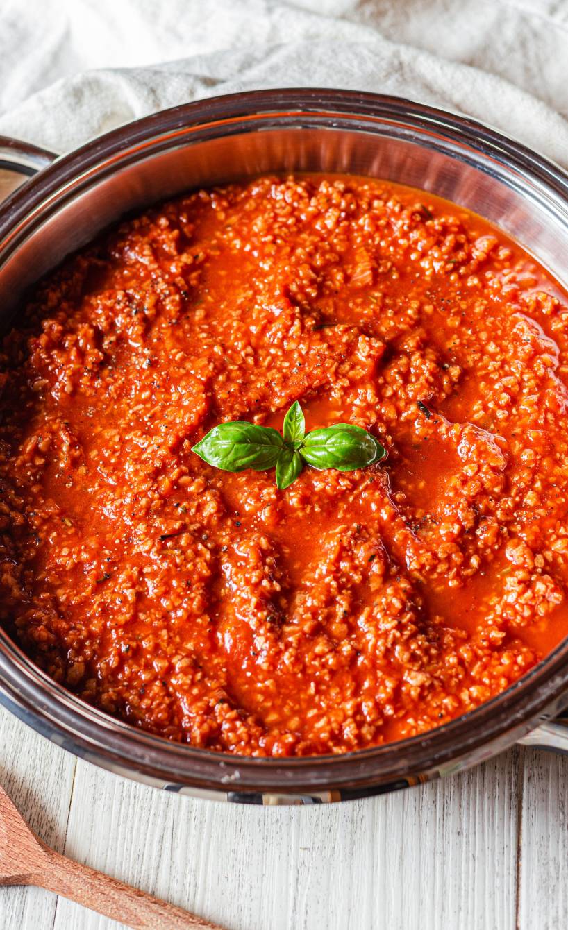 Bolognese Soße in einem Topf garniert mit frischem Basilikum auf einem Küchentisch